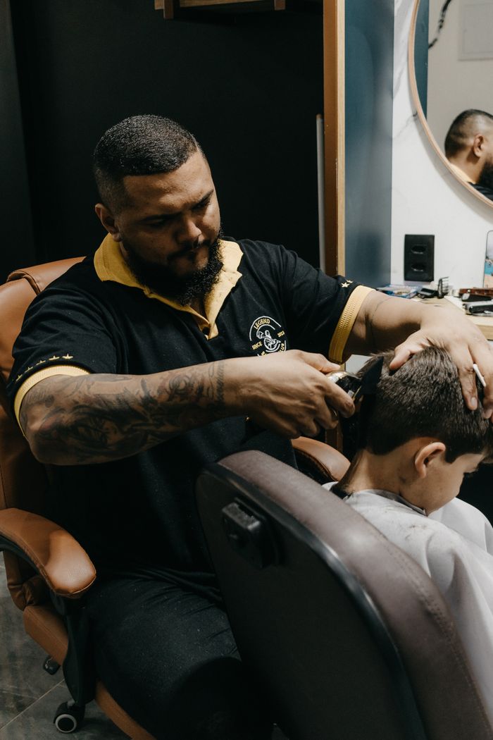 Barber skillfully cutting a young boy's hair in a modern barbershop setting.