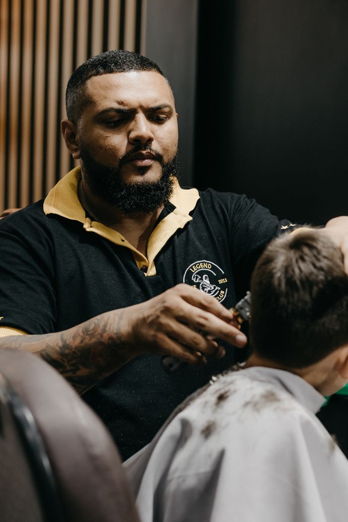 Barber skillfully giving a haircut to a young boy in a modern barbershop setting.