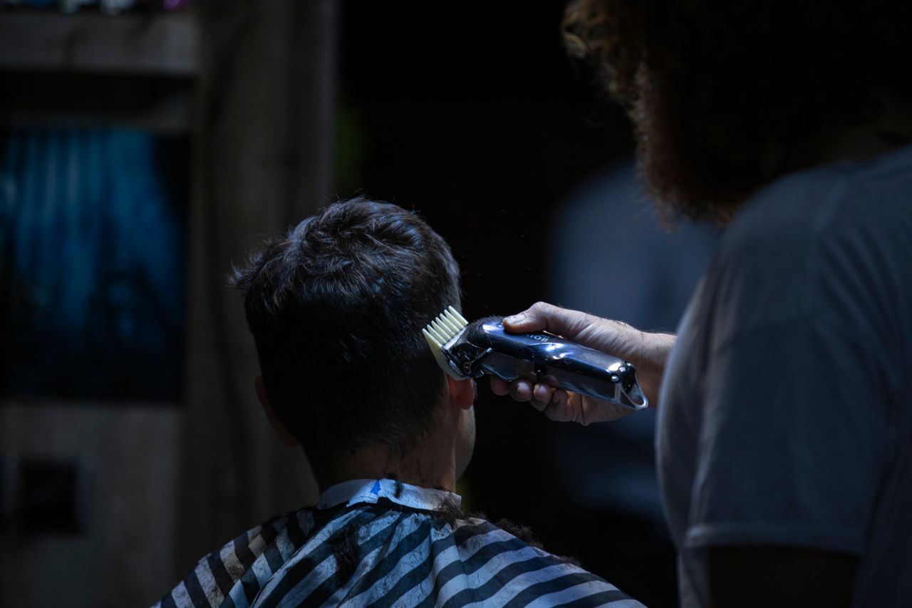Barber using electric clipper for a precise haircut in a barber shop.
