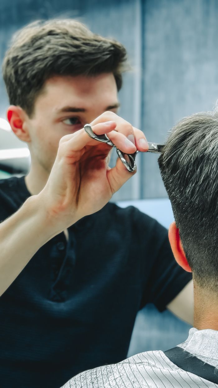 Barber skillfully cutting a customer's hair in a contemporary barbershop setting.