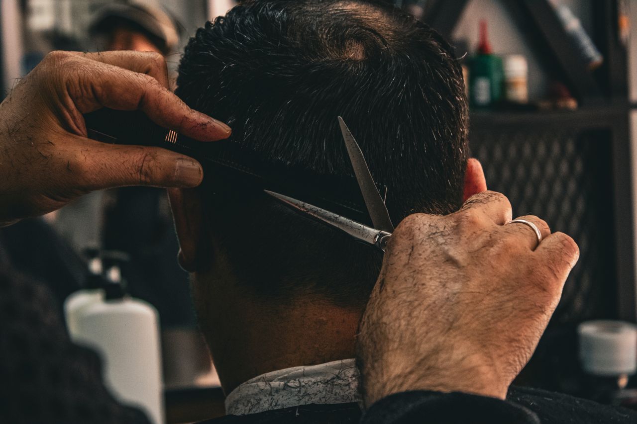 Close-up of a barber expertly cutting a client's hair, highlighting traditional grooming skills.