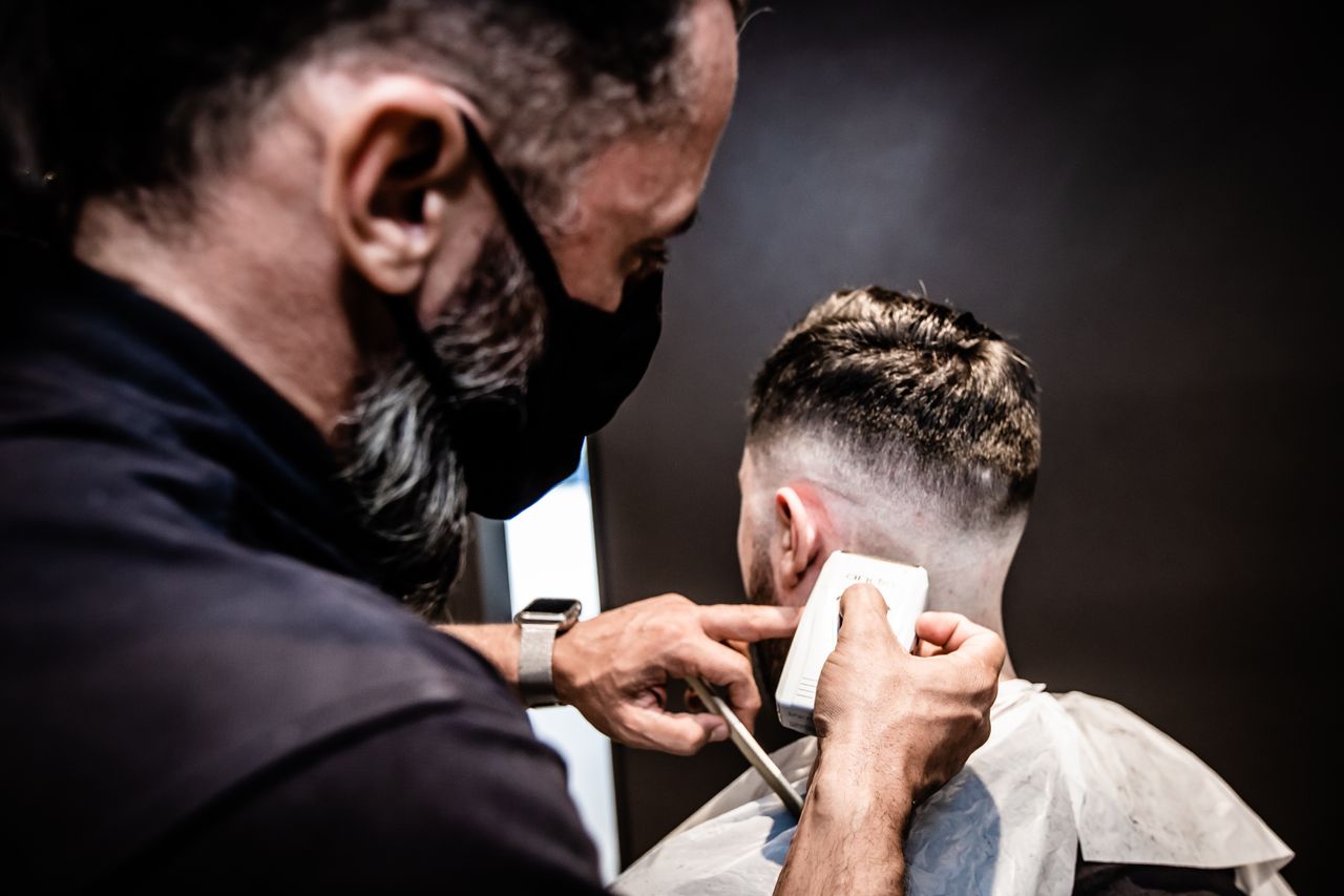 Barber performing a detailed haircut, showcasing precision and skill in an indoor setting.